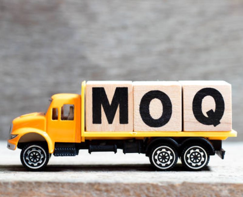 Truck hold letter block in word MOQ (Abbreviation of Minimum Order Quantity) on wood background